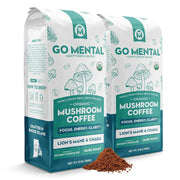 Two packages of Go Mental Mushroom Coffee with coffee grounds in front on a white background