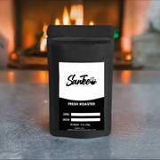Black coffee packaging with 'Santee' branding on a surface with a fireplace in the background