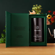 Green gift box with a black tea canister labeled 'Rare Leaves' on a wooden surface.