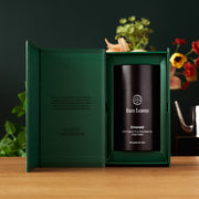 Tea canister labeled 'Rare Leaves' in a green box on a wooden surface with plants in the background.