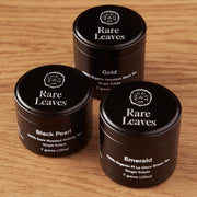 Three black containers labeled 'Rare Leaves' on a wooden surface