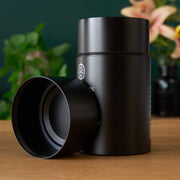 Black thermos with a lid on a wooden surface with a blurred background